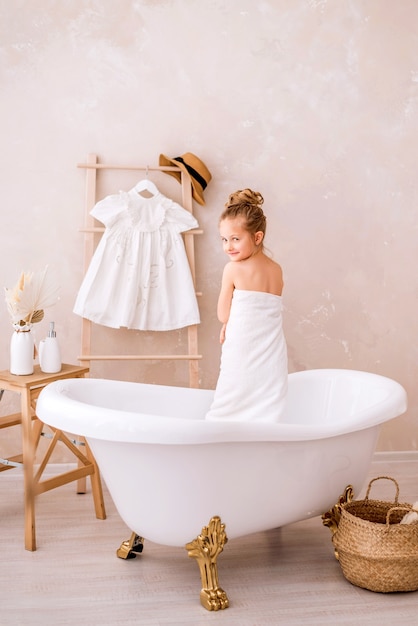 Cute girl in a big white towel in a bright bathroom