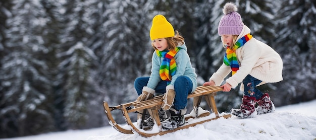 Cute girl and boy enjoying a sleigh ride children sledding in snow on winter park