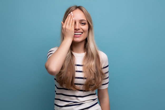 Cute girl in casual clothes covered her eyes with her hand on a blue isolated background