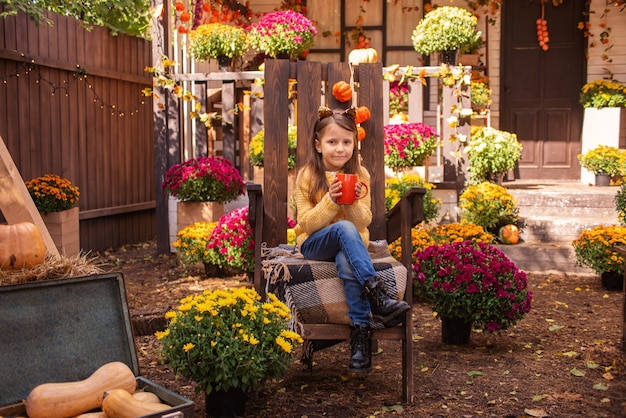 cute girl drinking tea outdoors in warm clothes in autumn halloween concept