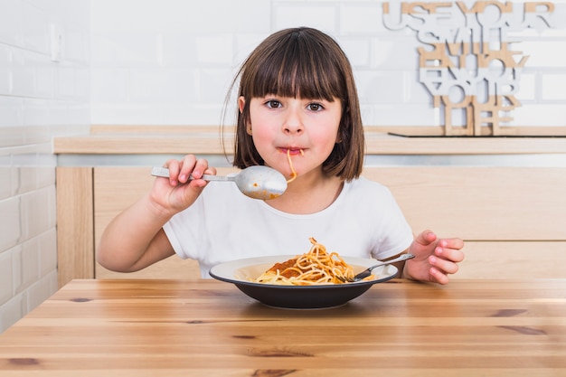 Cute girl eating tasty spaghetti