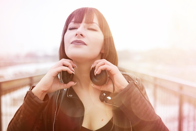 Cute girl in headphones listening to music outdoors