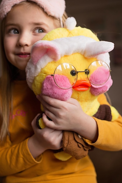 a cute girl holds in her hands a popular duckling with pink cheeks a yellow duck with glasses