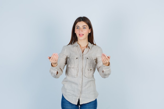 Cute girl inviting to come, looking away in shirt and looking wondered.