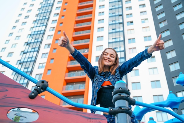 A cute girl is sitting on playground Happy caucasian girl in blue denim jacket