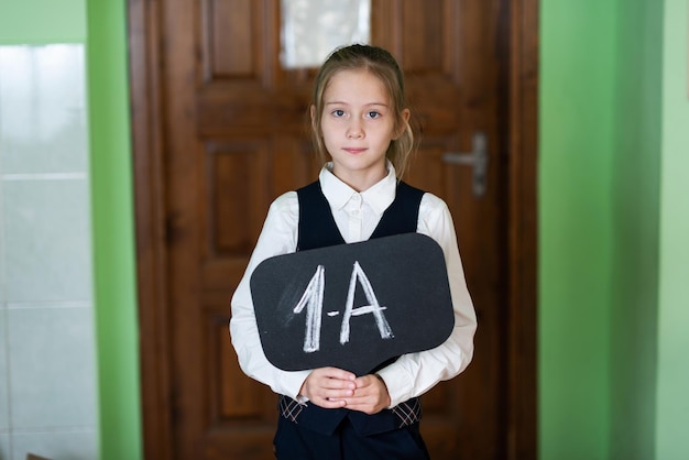 A cute girl is standing in the classroom with a grade 1 sign School life