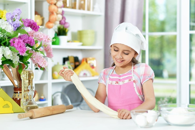 Cute girl making dough in the kitchen at home