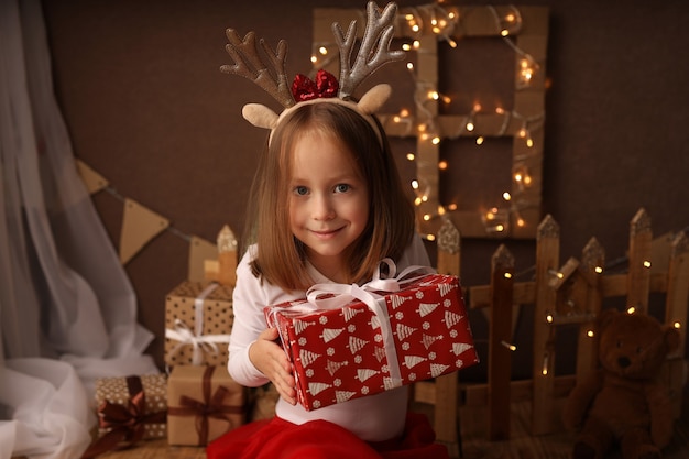 A cute girl in a New Years costume holds a New Years gift in a box