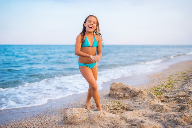 Cute girl playing on beach by sea