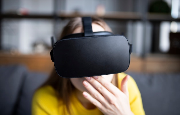 Cute girl plays the game on the console. Happy young woman using a virtual reality headset