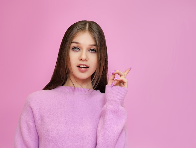 Cute girl points her finger up on a bright background