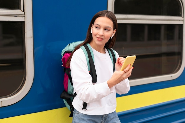 Cute girl at the railway station holding mobile phone