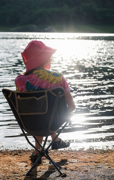 Cute girl in a rainbow-colored dress sitting on a chair at sunset