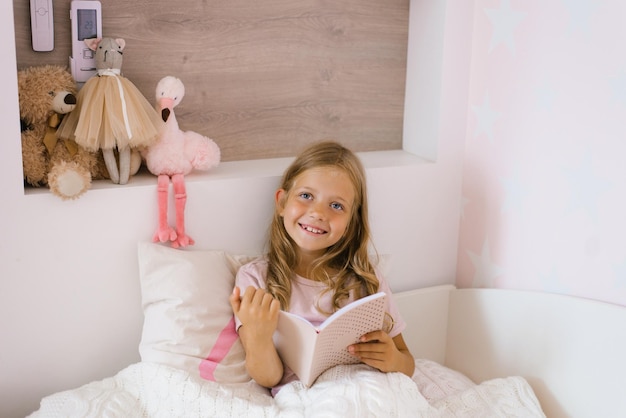 Cute girl reads a book lying in bed