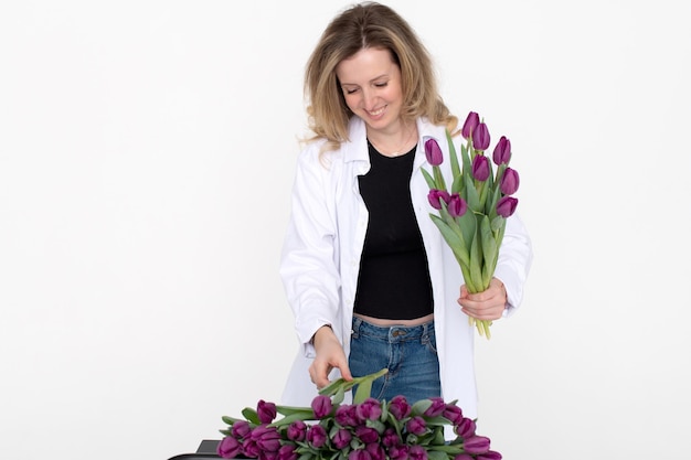 Cute girl in a shirt collects a bouquet of purple tulips for a gift to her mother