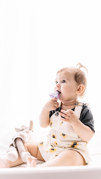 Cute girl sitting on cot and sucking toy