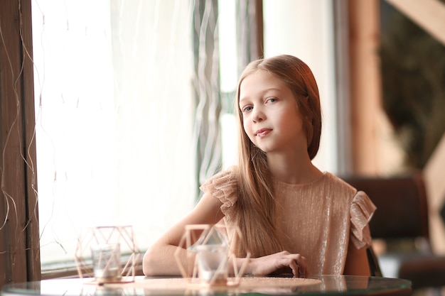 Cute girl sitting at a table in a cozy cafe