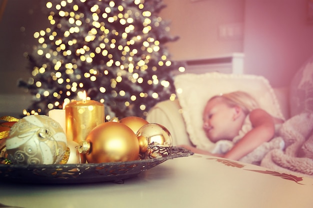 Cute girl sleeping on floor under Christmas tree