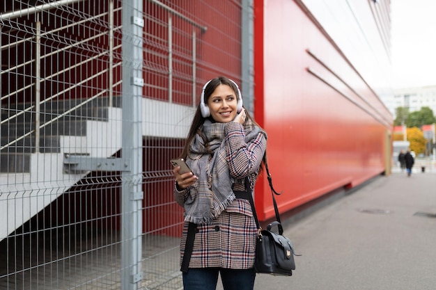 Cute girl tourist listens to music mobile app on the street