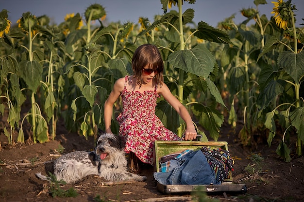 Cute girl with old suitcase in a sunflower field