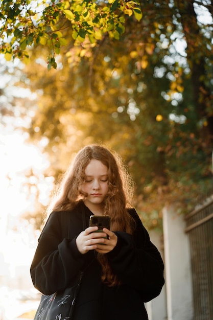 cute girl with smartphone in autumn park.