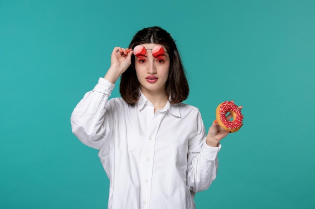 Cute girl young pretty adorable brunette girl in white shirt raising red glasses with donut