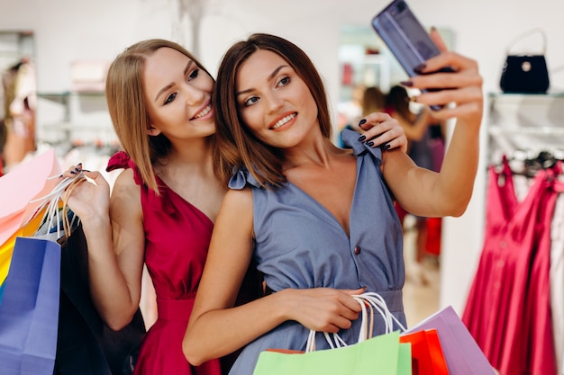 Cute girls some shopping at a boutique and taking a selfie with a smartphone