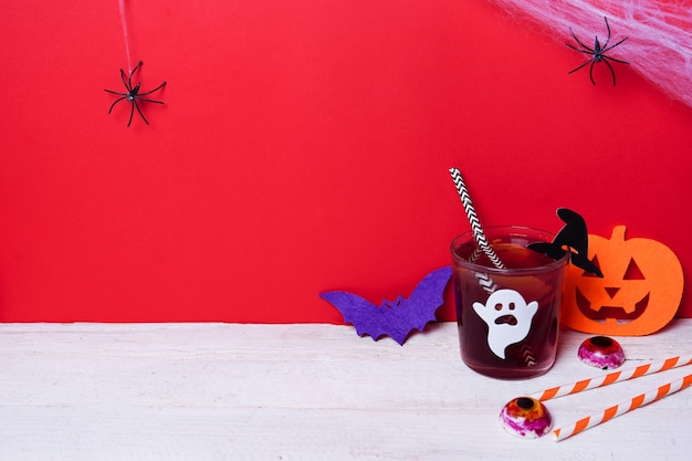 Cute Halloween drinks with pumpkin for a kids party on white wood with red scene