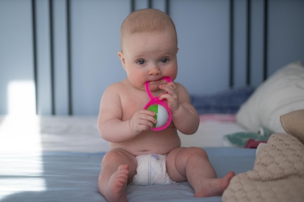 Cute happy 6 month baby girl in diaper lying and playing