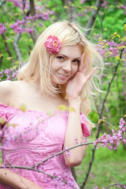 Cute happy blonde woman portrait in spring park near blossom tree