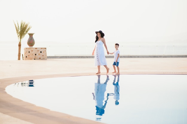 Cute happy family having fun near pool on luxury tropical resort, mother with child.