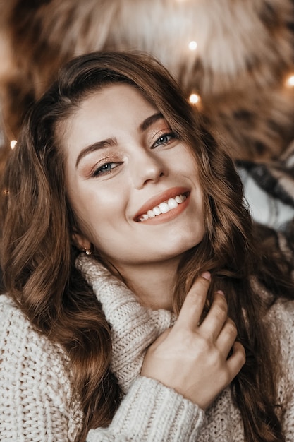 Cute happy girl in cozy sweater is smiling.