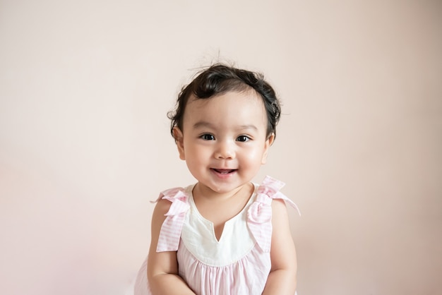 cute happy little asian baby girl isolated on beige background