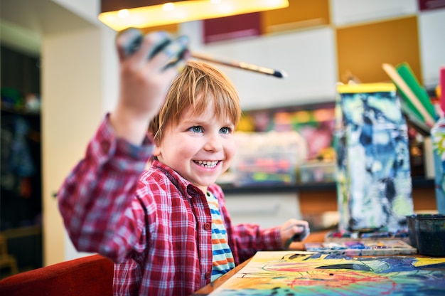 Cute happy little boy, adorable preschooler, painting in a sunny art studio.