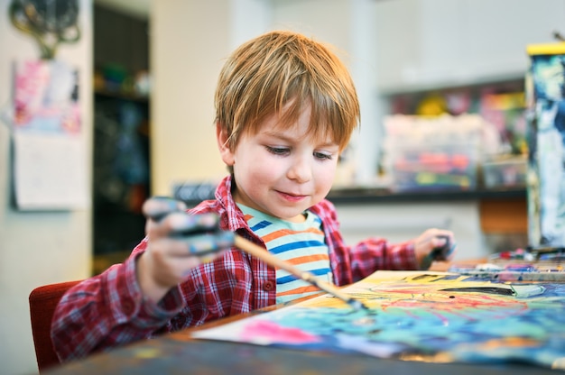 Cute happy little boy, adorable preschooler, painting in a sunny art studio