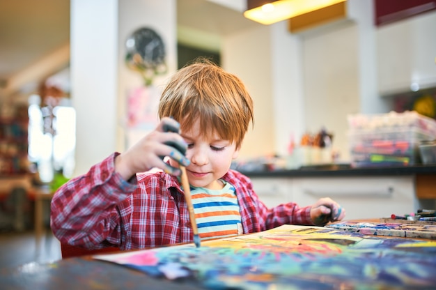 Cute happy little boy, adorable preschooler, painting in a sunny art studio.