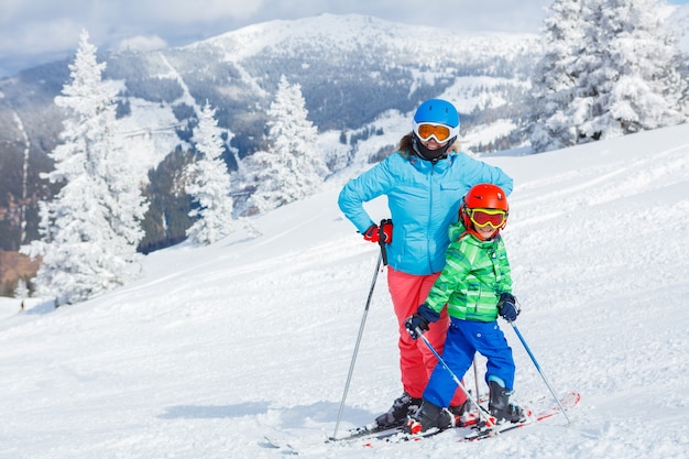 Cute happy skier boy with his mother in a winter ski resort.