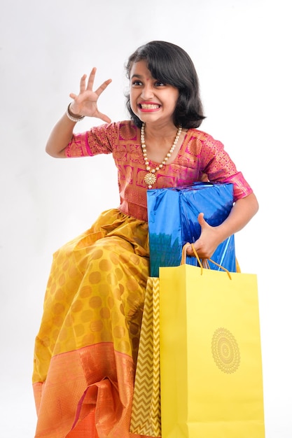 Cute indian little girl Child with gifts boxes and shopping bag standing on white background