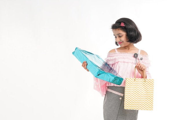 Cute indian little girl Child with gifts boxes and shopping bag standing on white background