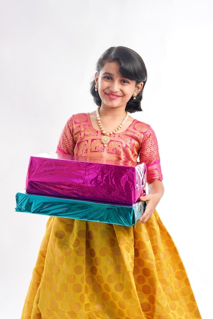 Cute indian little girl Child with gifts boxes in traditional cloths standing isolated over white background