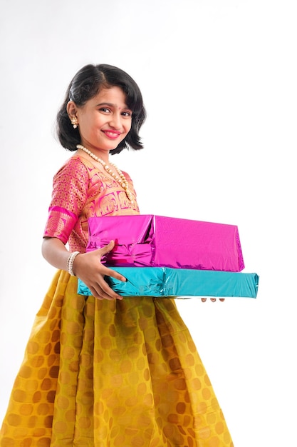 Cute indian little girl Child with gifts boxes in traditional cloths standing isolated over white background