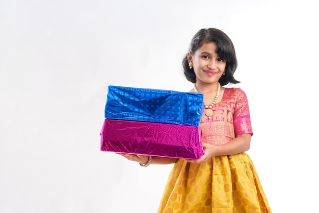 Cute indian little girl Child with gifts boxes in traditional cloths standing isolated over white background