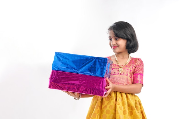 Cute indian little girl Child with gifts boxes in traditional cloths standing isolated over white background