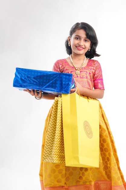 Cute indian little girl Child with gifts boxes in traditional cloths standing isolated over white background