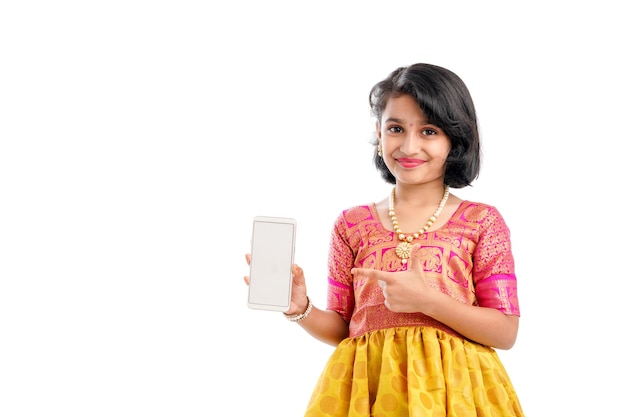 Cute indian little girl showing smartphone screen on white background