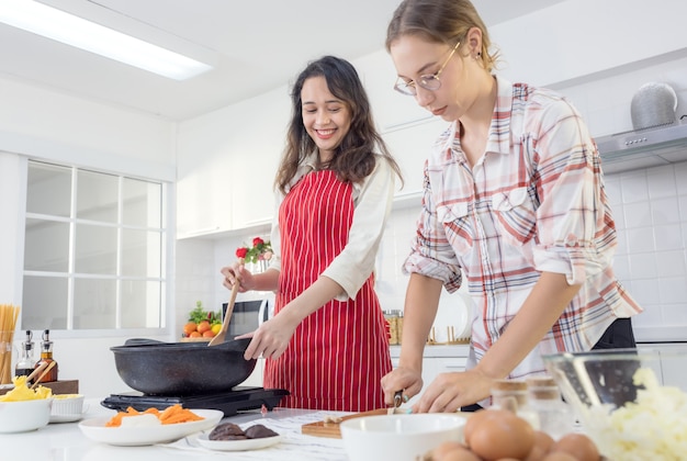 Cute joyful couple cooking together and adding spice to meal