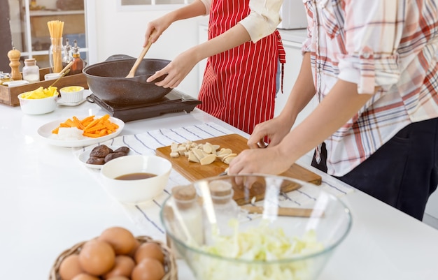 Cute joyful couple cooking together and adding spice to meal