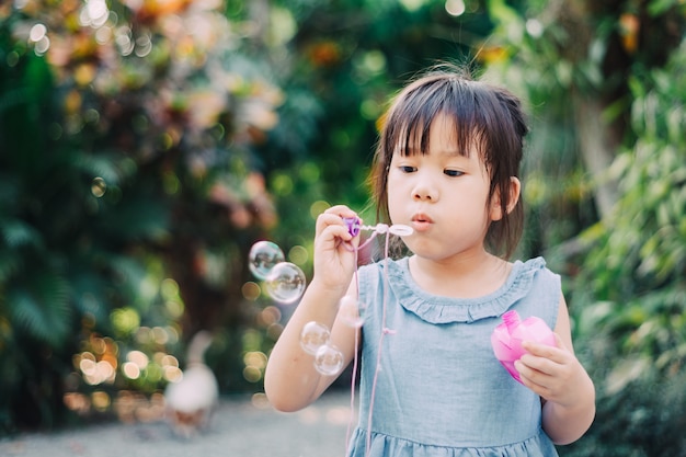 Cute kid blowing bubbles soap in the  garden.