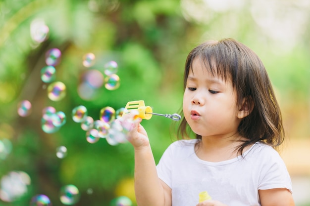 Cute kid blowing bubbles soap in the  garden