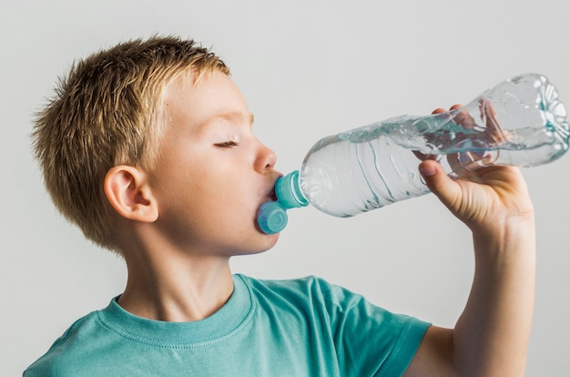 Cute kid drinking water from a plastic bottle